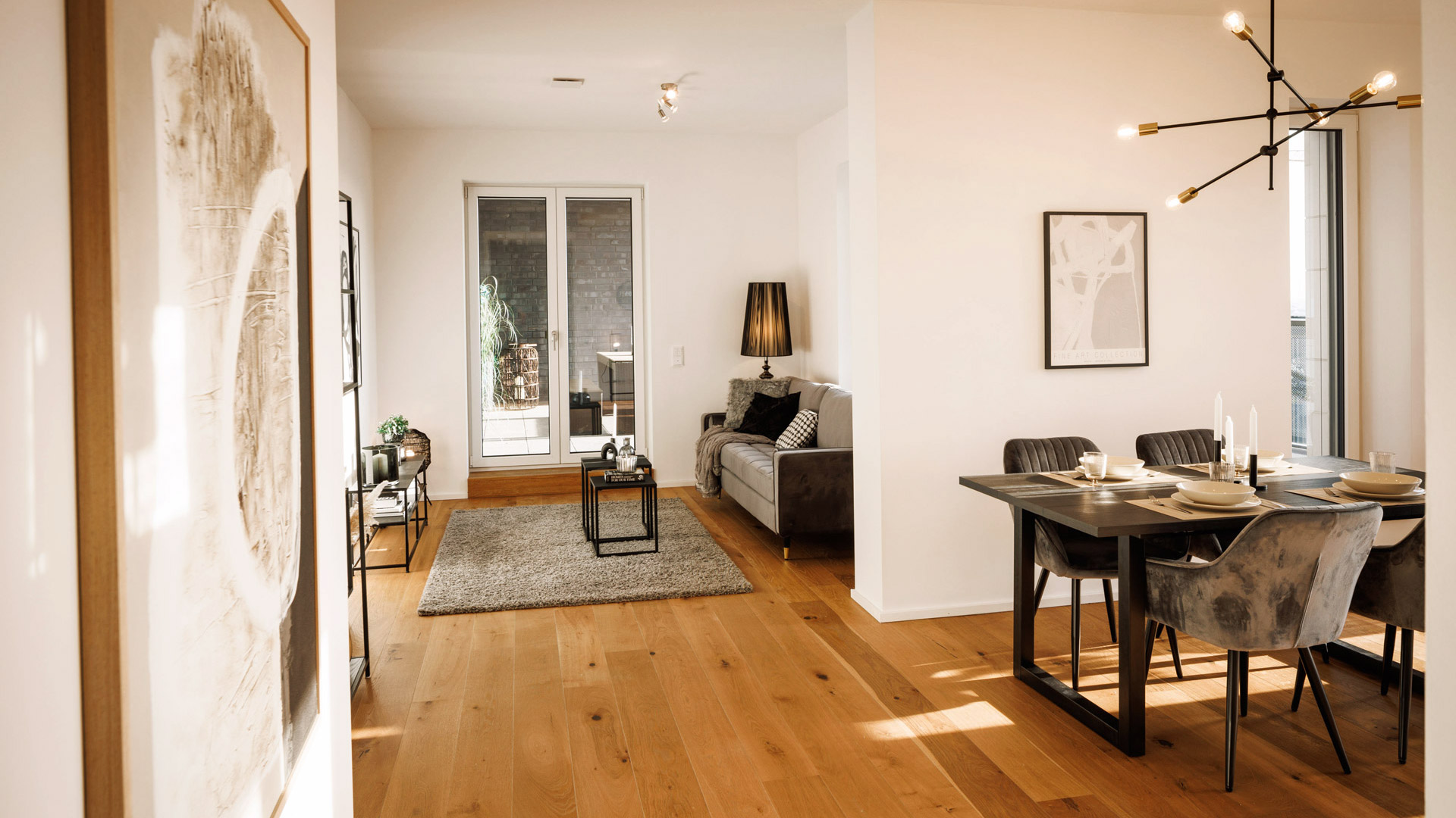 KI-basierte Bildbeschreibung: Ein moderner, offener Wohn- und Essbereich mit Holzböden, neutralem Dekor, einem grauen Sofa, einer schwarzen Lampe, einem abstrakten Kunstwerk und einem Esstisch für vier Personen in der Nähe großer Fenster.